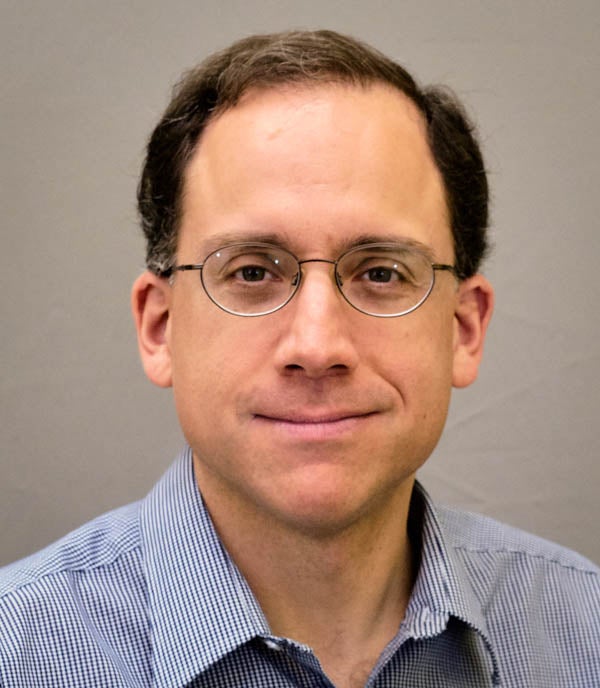 Portrait Headshot of Greg Keller. Man with short brown hair and glasses.