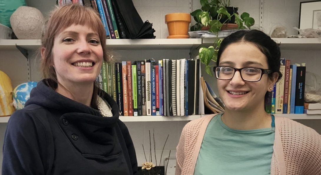 Kelsey Foss and Martha Madera posing in an office with textbooks in the background.