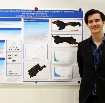 Louis Quigley stands in front of his winning poster.
                  